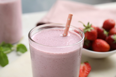 Tasty milk shake with straw on light table, closeup