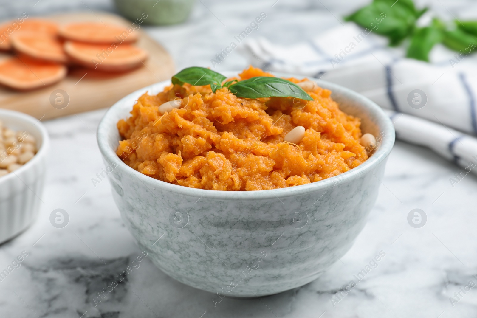 Photo of Bowl of tasty sweet potato puree on marble table