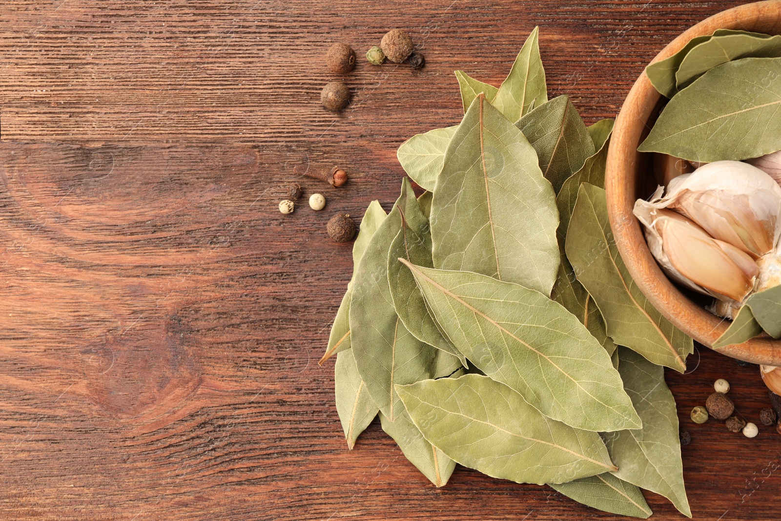 Photo of Aromatic bay leaves and spices on wooden table, flat lay. Space for text