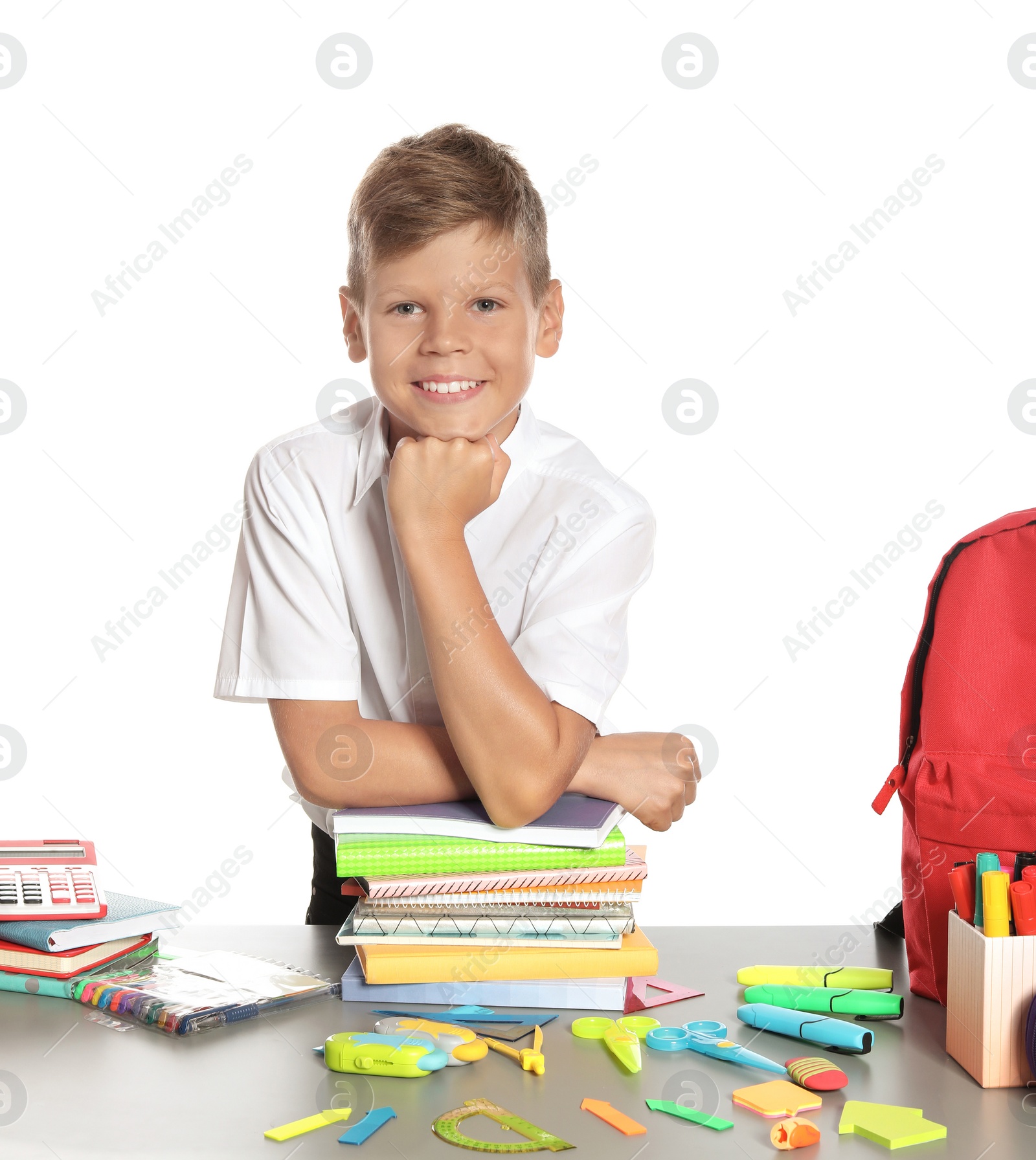 Photo of Schoolboy at table with stationery against white background