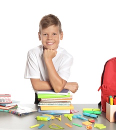 Schoolboy at table with stationery against white background