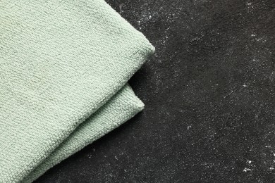 Soft terry towel on black textured background, top view. Space for text