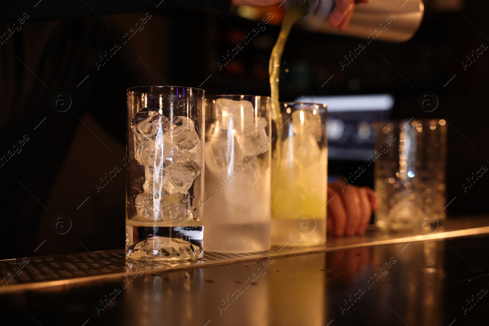 Photo of Bartender pouring energy drink into glass at counter in bar, selective focus