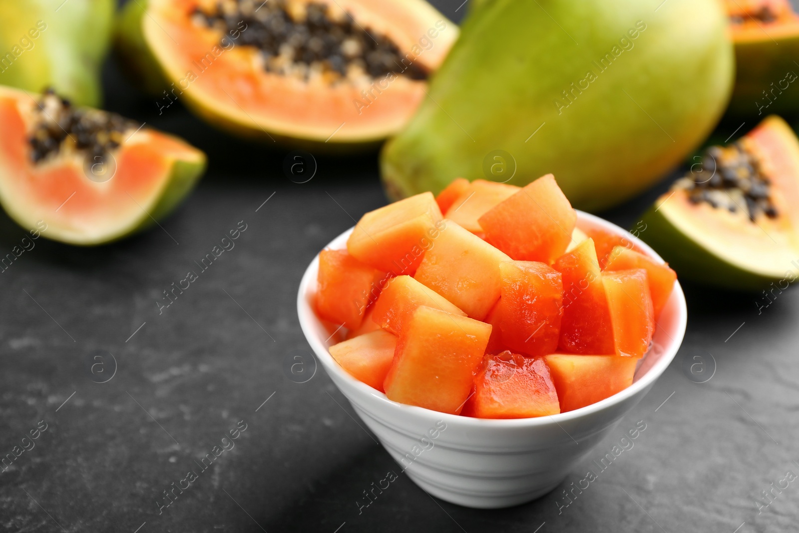 Photo of Dices of fresh ripe papaya in bowl on black table