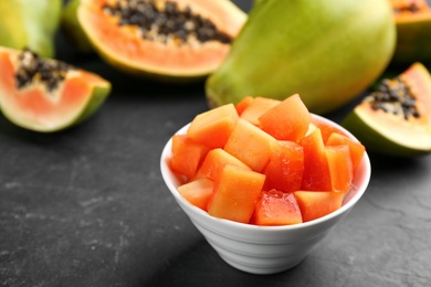 Dices of fresh ripe papaya in bowl on black table