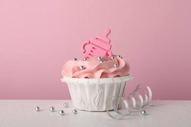 Photo of Baby shower cupcake with topper on white table against pink background