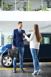 Salesperson giving car key to man in auto dealership