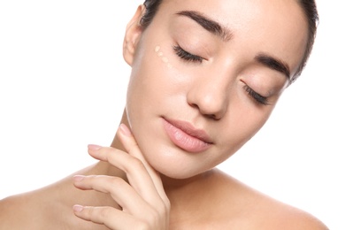 Portrait of young woman with liquid foundation on her face against white background