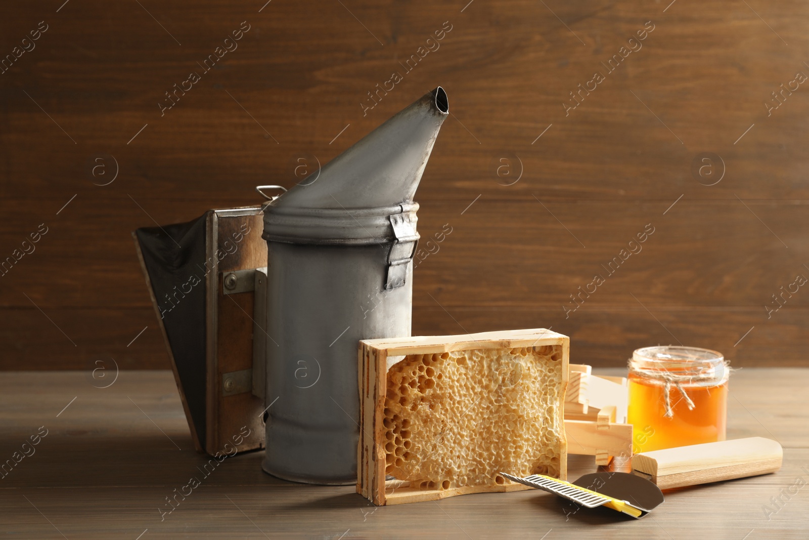 Photo of Composition with honeycomb and beekeeping tools on wooden table