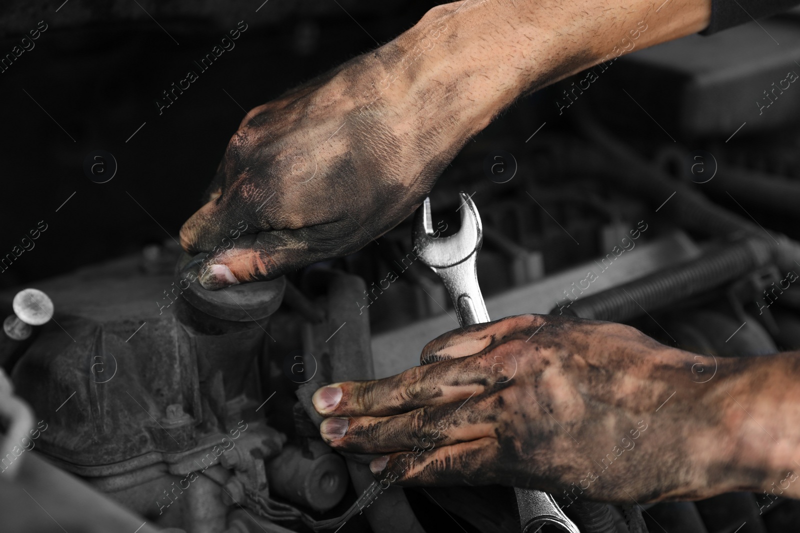 Photo of Dirty mechanic fixing car, closeup of hands