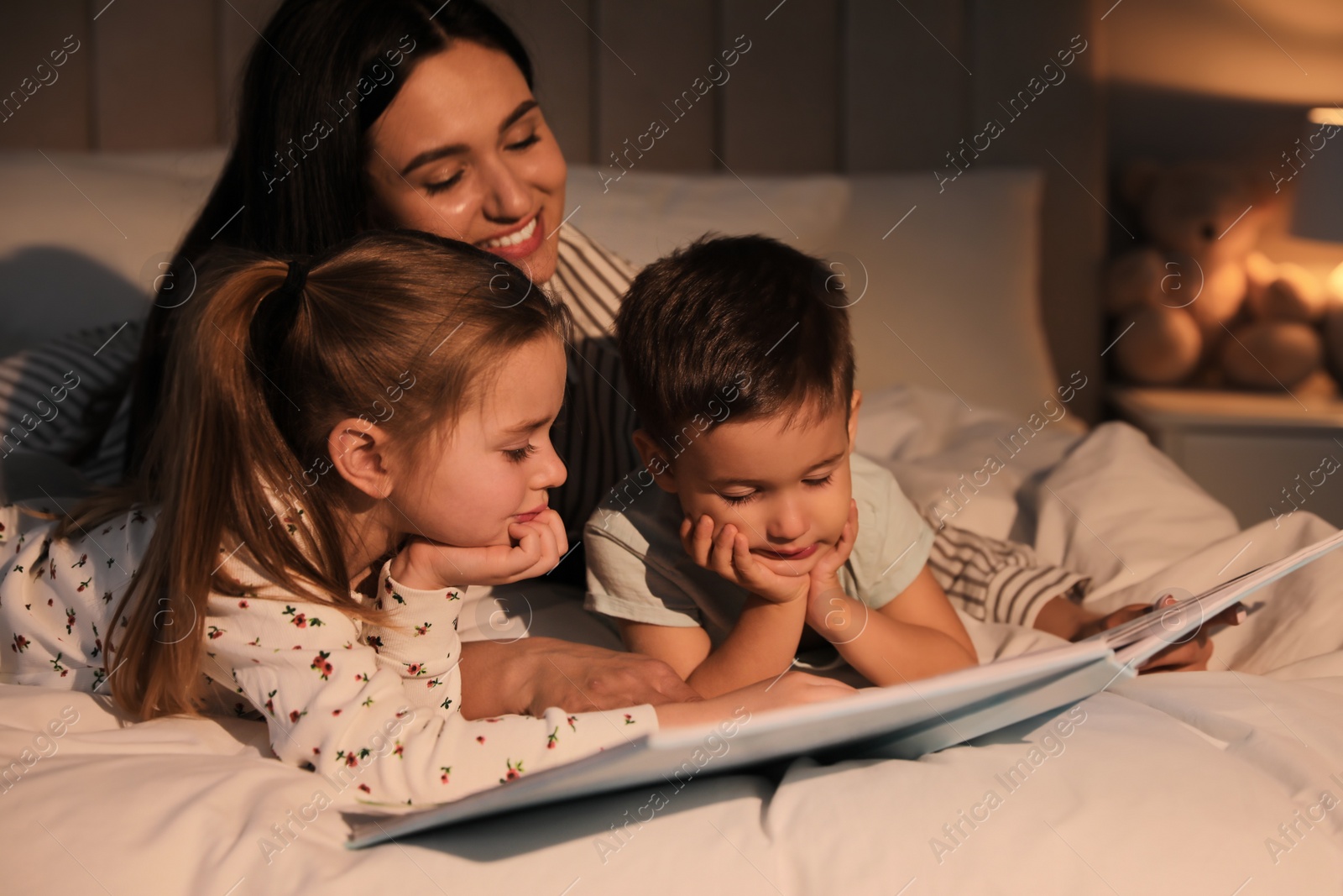 Photo of Mother reading bedtime story to her children at home