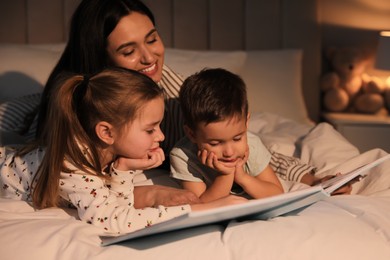 Photo of Mother reading bedtime story to her children at home