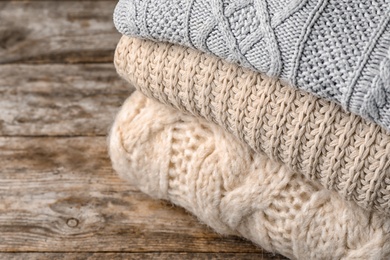 Photo of Stack of folded knitted sweaters on table, closeup