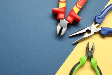 Photo of Different pliers on color background, flat lay. Space for text