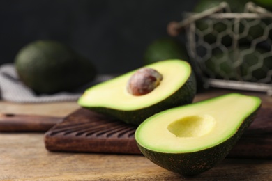 Halves of delicious ripe avocado on wooden table