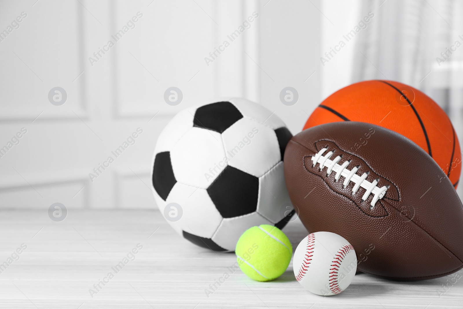 Photo of Set of different sport balls on white wooden table indoors. Space for text