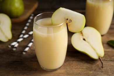 Photo of Fresh pear juice in glass and fruits on wooden table, closeup