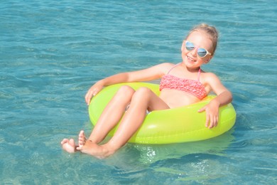 Happy little girl with inflatable ring in sea on sunny day