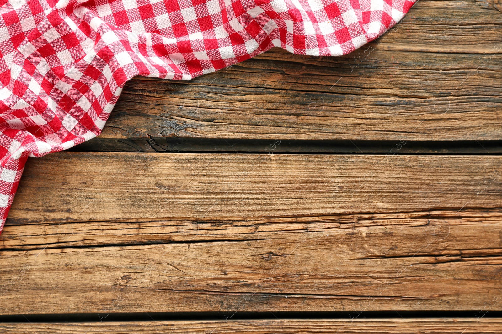 Photo of Checkered picnic tablecloth on wooden background, top view