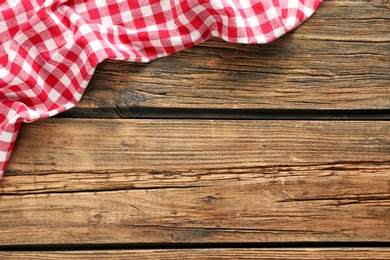 Checkered picnic tablecloth on wooden background, top view