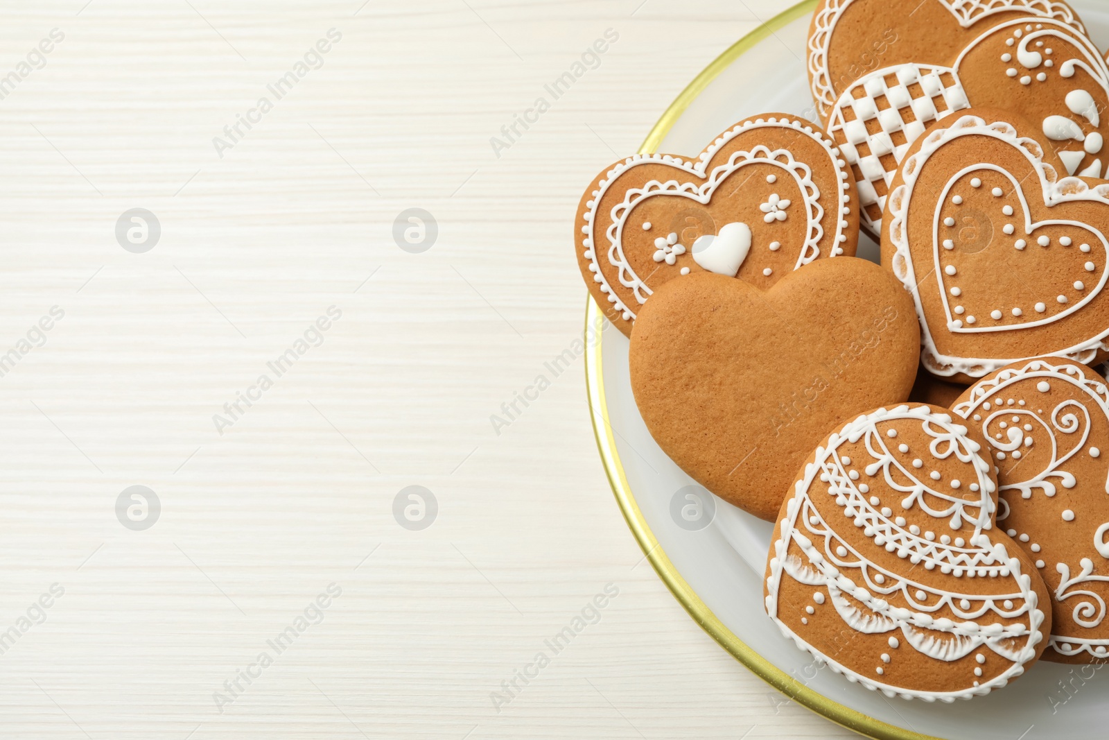 Photo of Tasty heart shaped gingerbread cookies on white wooden table, top view. Space for text