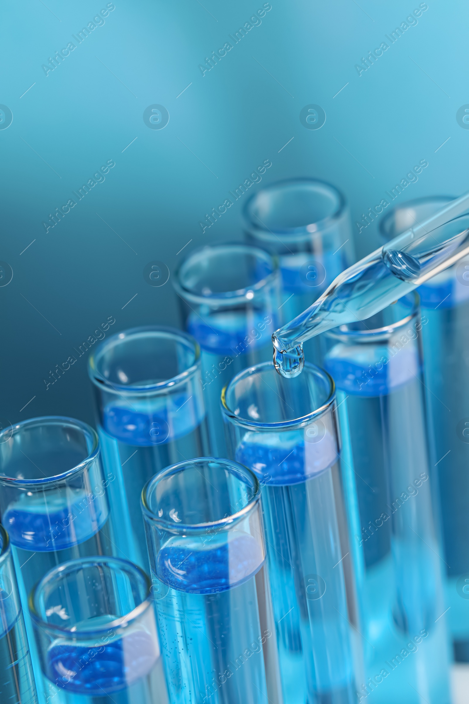 Photo of Dripping reagent into test tube on light blue background, closeup. Laboratory analysis