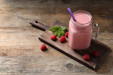 Yummy raspberry smoothie in mason jar on wooden table. Space for text