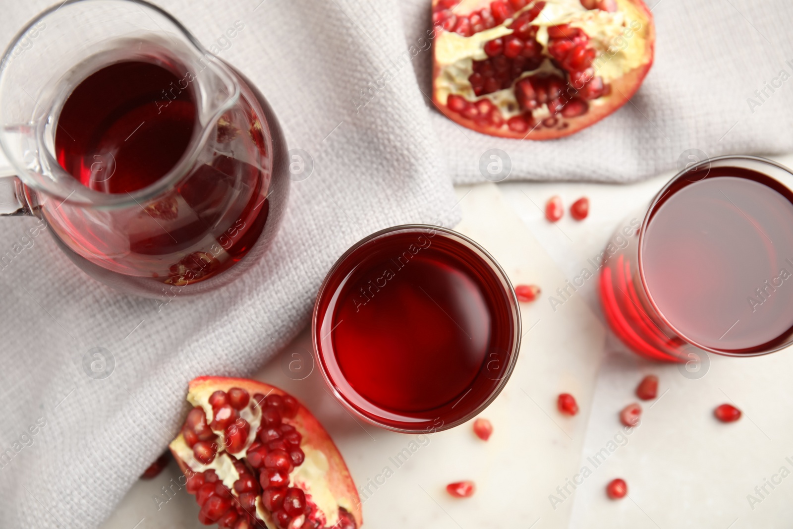 Photo of Freshly made pomegranate juice on light table, flat lay