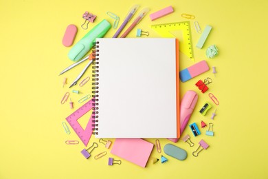 Photo of Flat lay composition with notebook and different school stationery on pale yellow background. Back to school