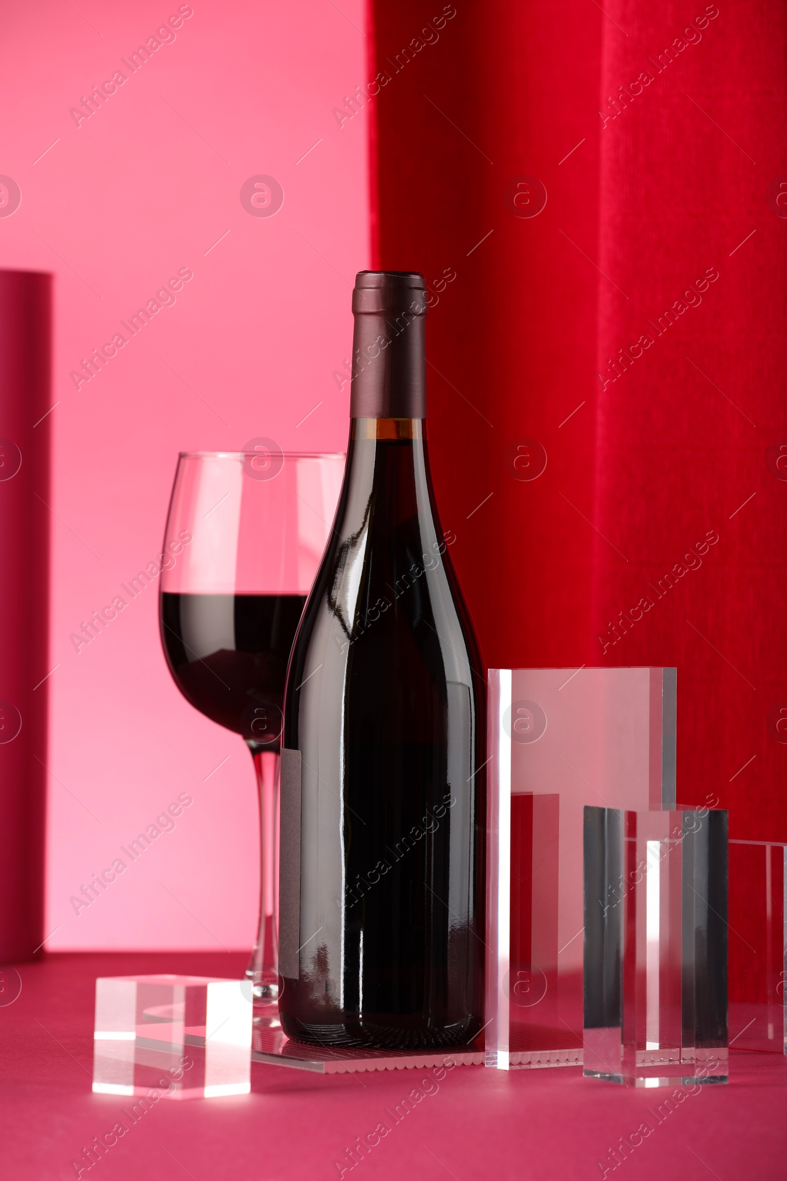 Photo of Stylish presentation of delicious red wine in bottle and glass on color background