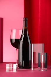 Photo of Stylish presentation of delicious red wine in bottle and glass on color background