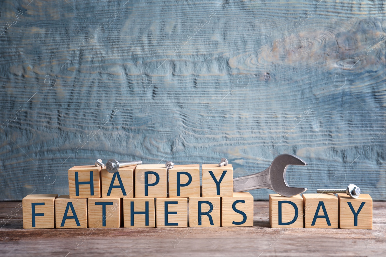 Photo of Wooden cubes and wrench on table. Father's day celebration