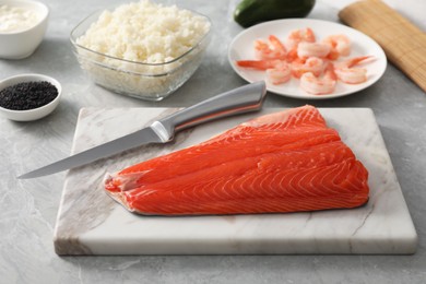 Fresh salmon and other ingredients for sushi on grey marble table, closeup