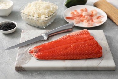 Photo of Fresh salmon and other ingredients for sushi on grey marble table, closeup