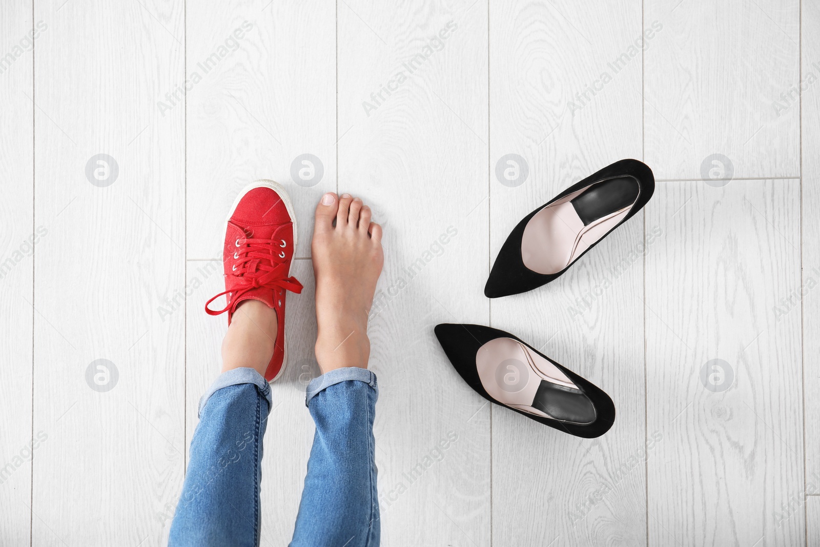 Photo of Young woman changing shoes on wooden background, top view