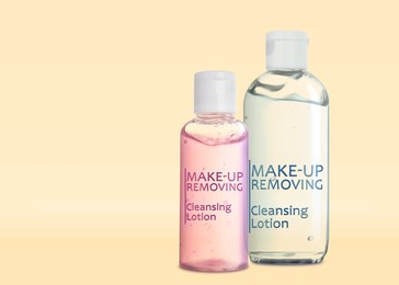 Image of Bottles of cleansing lotions on beige background, space for text. Makeup remover 