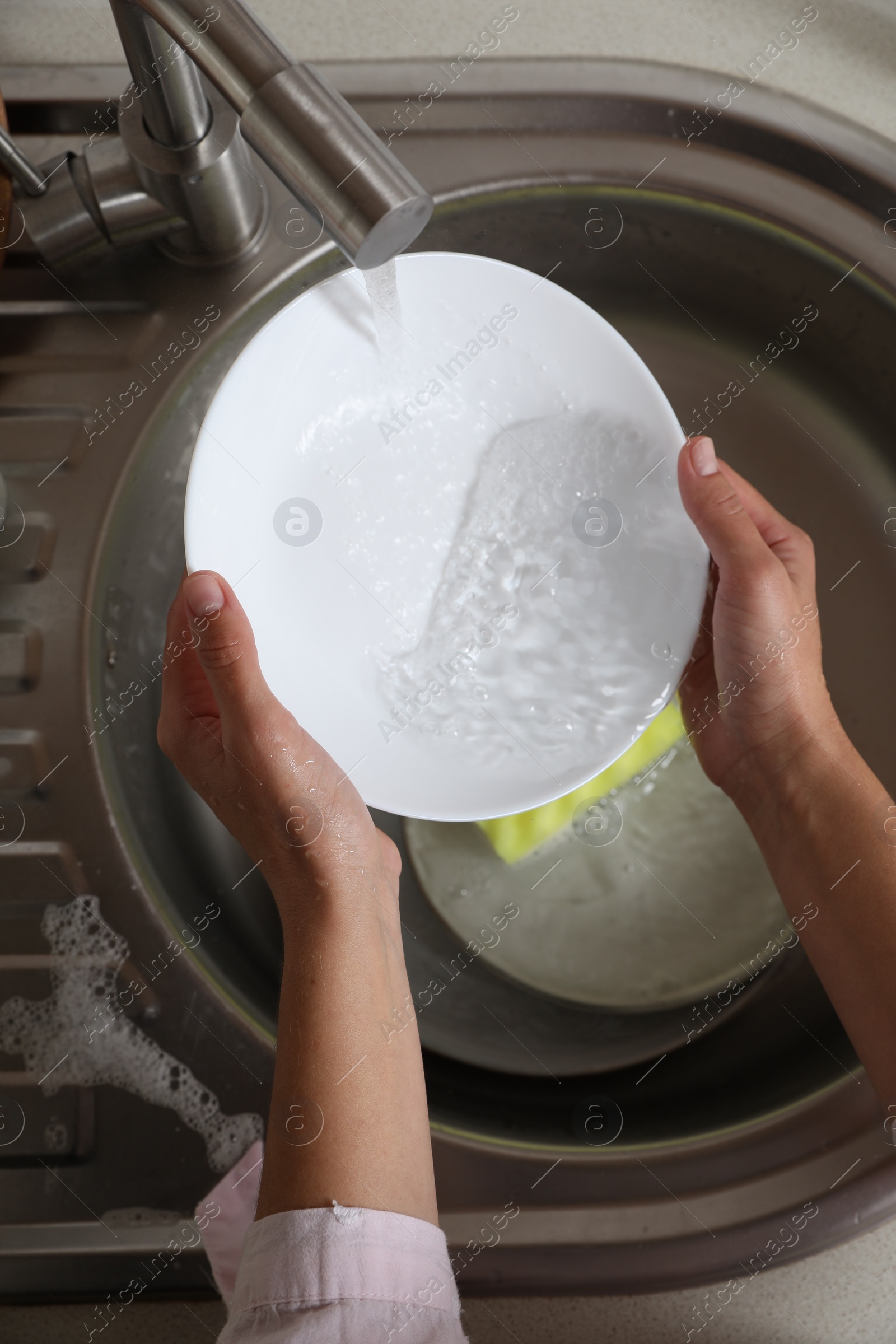 Photo of Woman washing plate in kitchen sink, above view