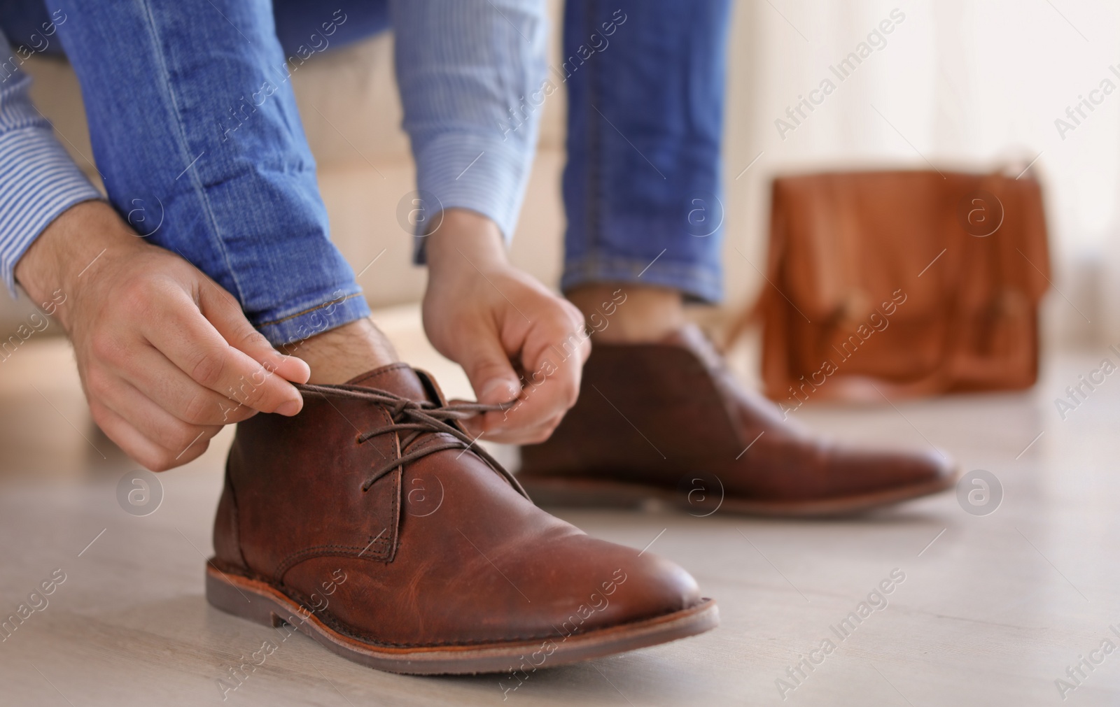 Photo of Man putting on elegant leather shoes indoors, closeup