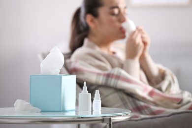 Photo of Nasal spray bottles, napkins and blurred view of sick woman on background