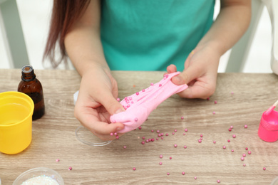 Little girl making homemade slime toy at table, closeup