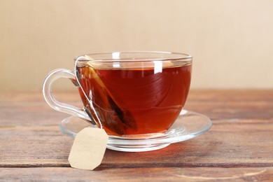 Photo of Brewing aromatic tea. Cup with teabag on wooden table