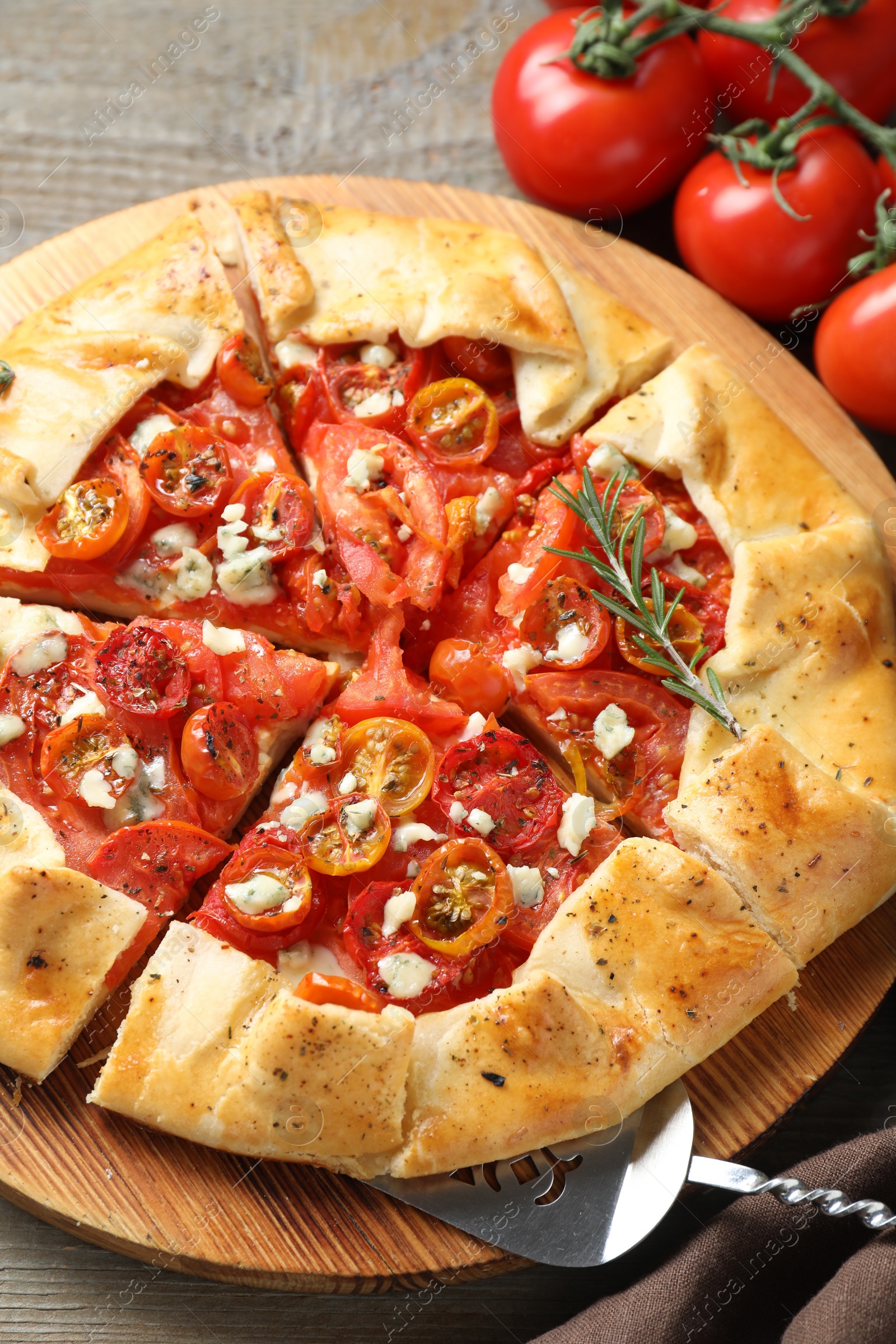 Photo of Tasty galette with tomato, rosemary and cheese (Caprese galette) on wooden table, closeup