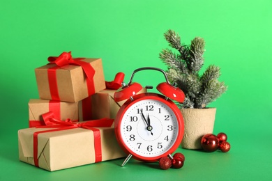 Alarm clock with Christmas decor on green background. New Year countdown