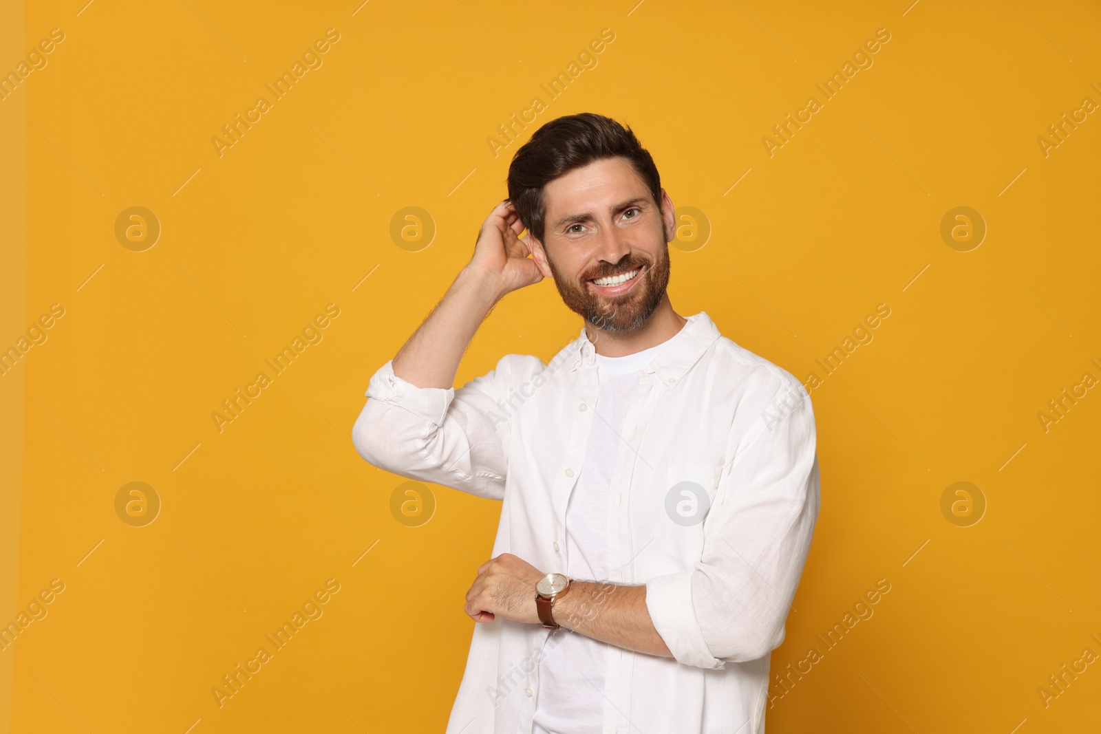 Photo of Portrait of smiling bearded man with wristwatch on orange background