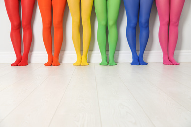Photo of Women wearing colorful tights near white wall, closeup