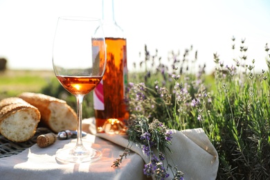 Photo of Composition with glass of wine on wicker table in lavender field. Space for text