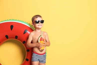 Photo of Cute little boy with inflatable ring and glass of cocktail on color background