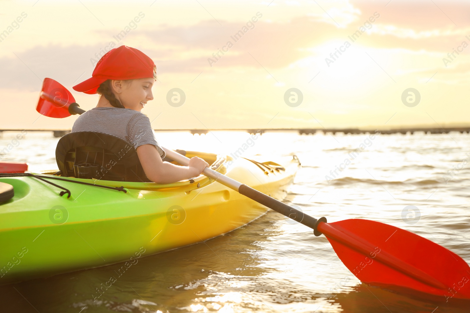 Photo of Little girl kayaking on river, back view. Summer camp activity