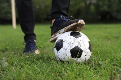 Photo of Man with dirty soccer ball on green grass outdoors, closeup