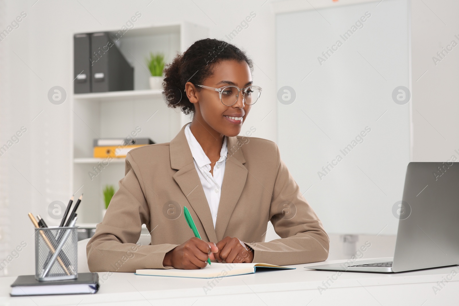 Photo of African American intern working at white table in office